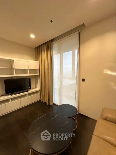 Modern living room with sleek furniture and large window offering natural light.