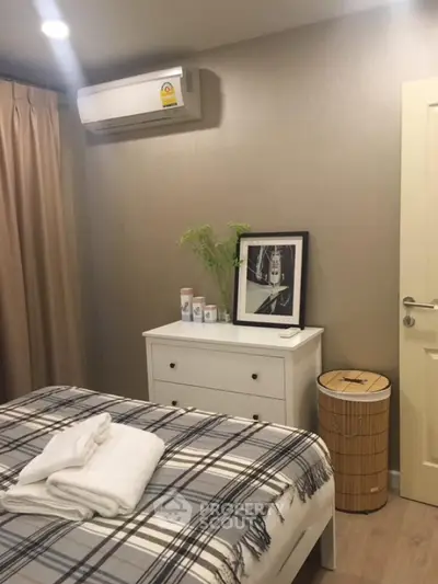 Cozy bedroom with modern decor and air conditioning, featuring a stylish dresser and framed artwork.