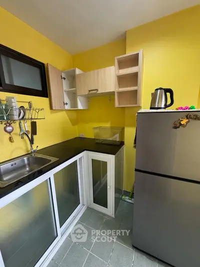 Compact kitchen with vibrant yellow walls and modern stainless steel appliances.