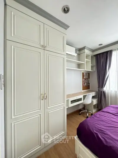 Elegant bedroom with built-in wardrobe and study desk, featuring natural light and stylish decor.