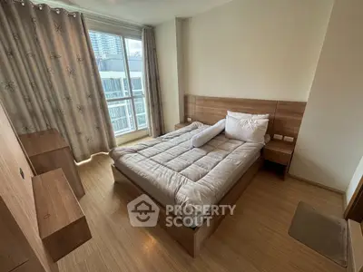 Cozy bedroom with modern furnishings and large window offering city views, perfect for urban living.