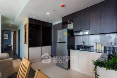 Modern kitchen with sleek cabinets and stainless steel fridge in open layout apartment.