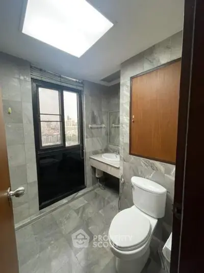 Modern bathroom with city view, featuring sleek gray tiles and contemporary fixtures.