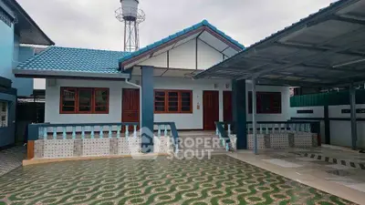 Charming single-story home with blue roof and spacious front yard, perfect for family living.