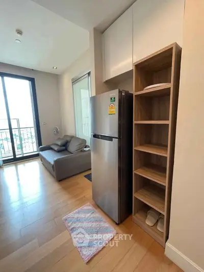 Modern apartment interior with sleek kitchen and cozy living area featuring a large window and balcony access.