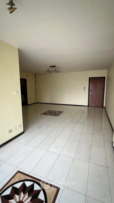 Spacious empty living room with tiled flooring and elegant ceiling light fixture.