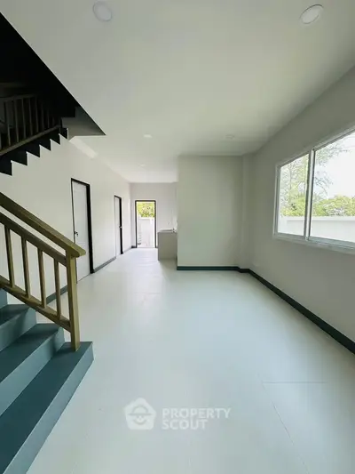 Spacious modern interior with staircase and large window, perfect for natural light.