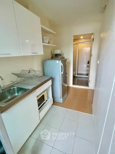 Compact kitchen with modern appliances and sleek cabinetry in a cozy apartment setting.