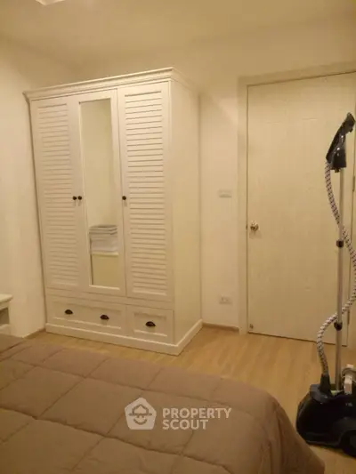 Cozy bedroom with wardrobe and modern steamer, perfect for comfortable living.