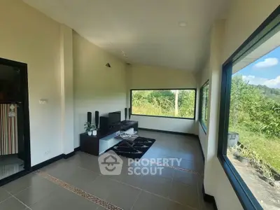 Spacious living room with large windows offering scenic views of lush greenery.