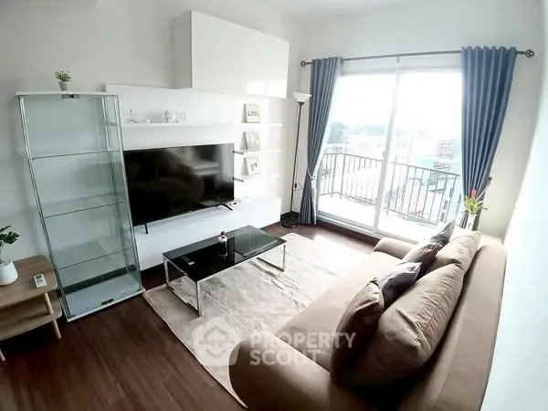 Modern living room with large sofa, glass coffee table, and balcony view.