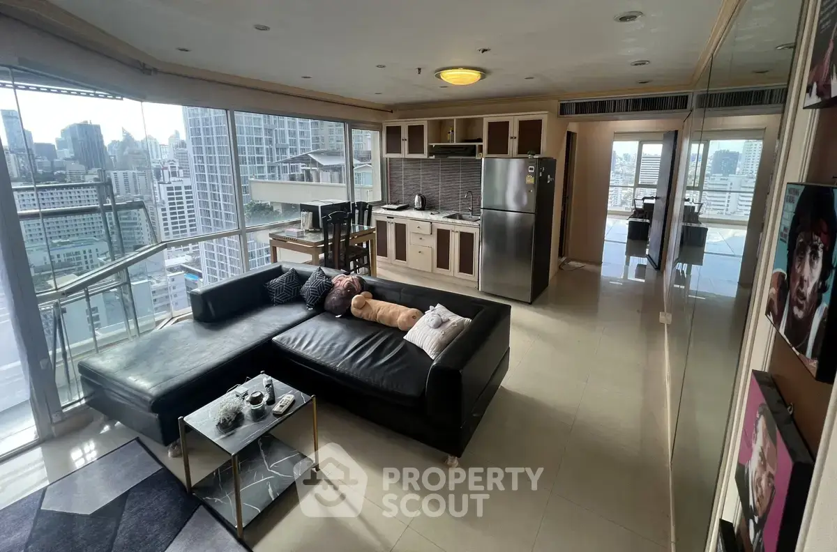 Modern open-plan living room with city view, featuring sleek kitchen and stylish decor.