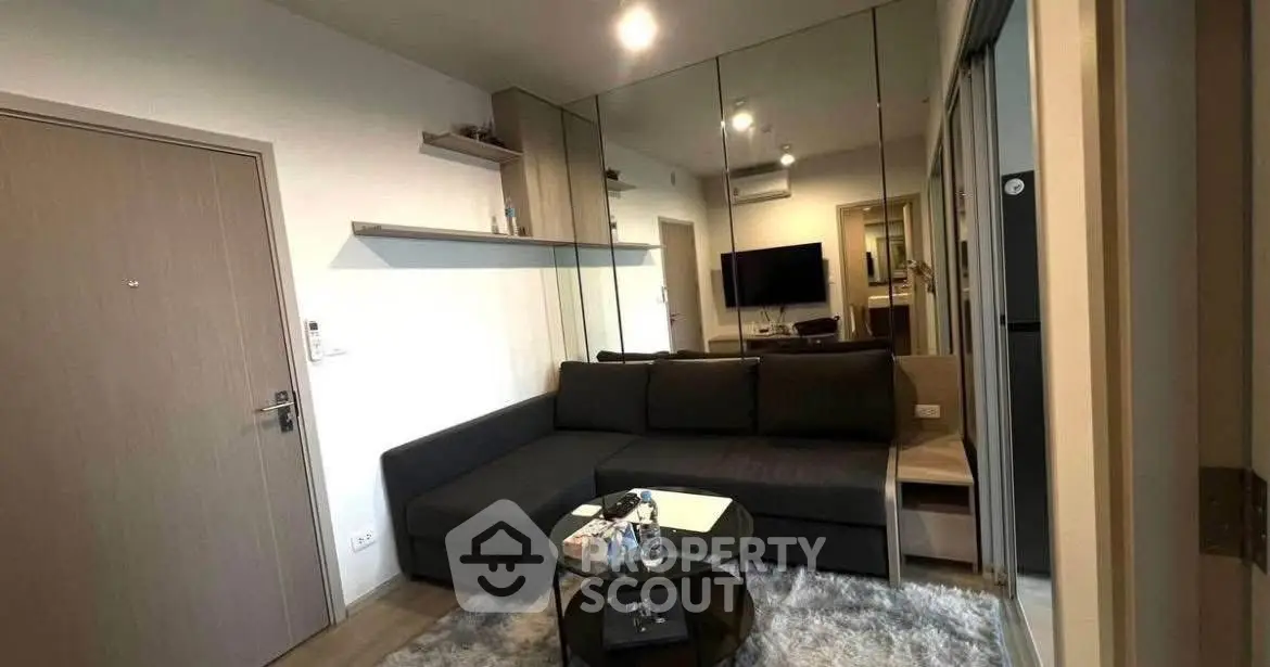 Modern living room with sleek black sofa and mirrored wall