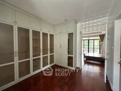 Spacious bedroom with elegant wooden flooring and built-in wardrobes