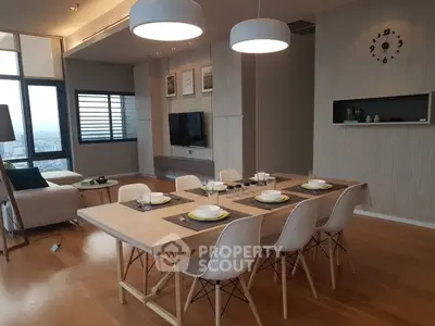 Modern dining area with elegant table setting and stylish lighting in open-plan living space.