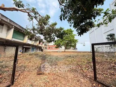 Spacious vacant lot with potential for development, surrounded by residential buildings and lush greenery.