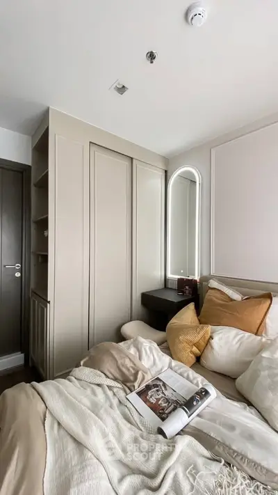 Cozy bedroom with elegant decor and soft lighting, featuring a stylish mirror and plush bedding.