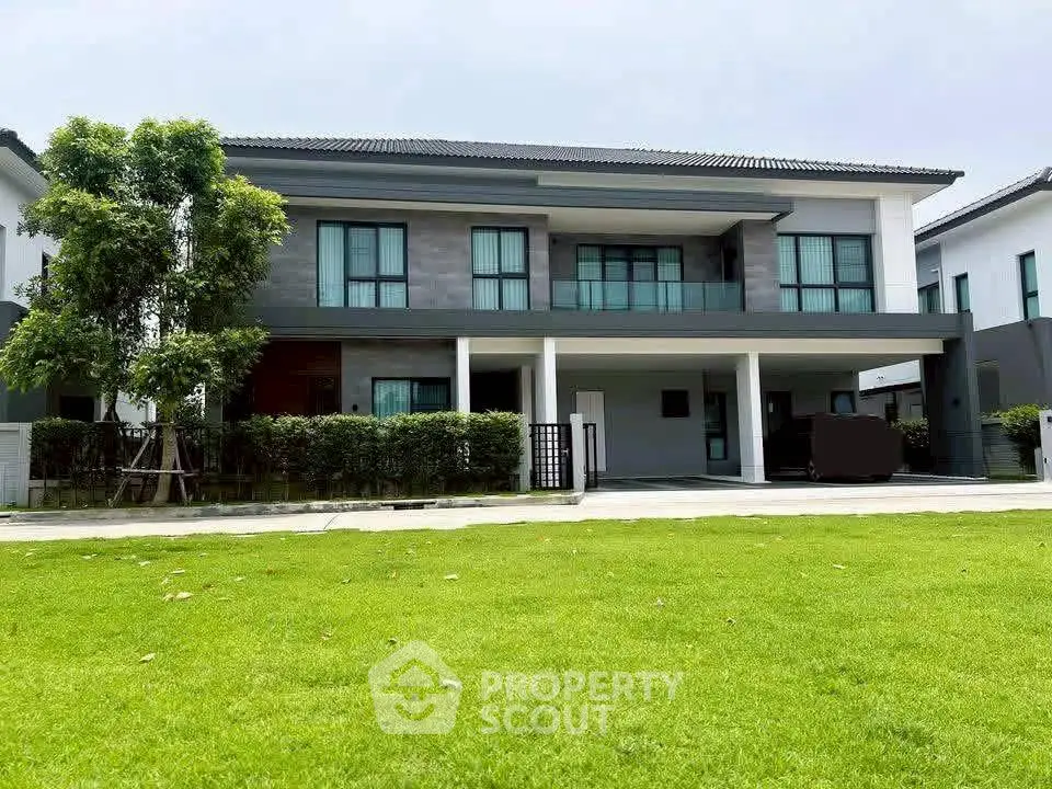 Modern two-story house with large windows and lush green lawn