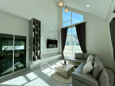 Spacious modern living room with high ceilings and large windows, featuring elegant decor and ample natural light.