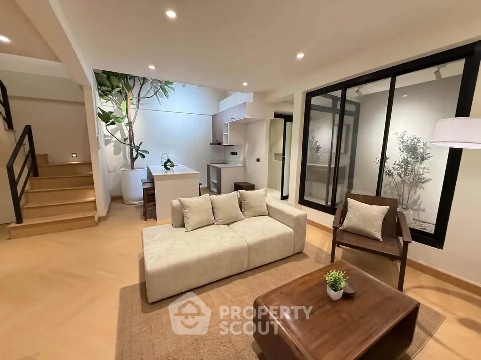 Modern living room with open layout, stylish furniture, and indoor plants creating a cozy ambiance.