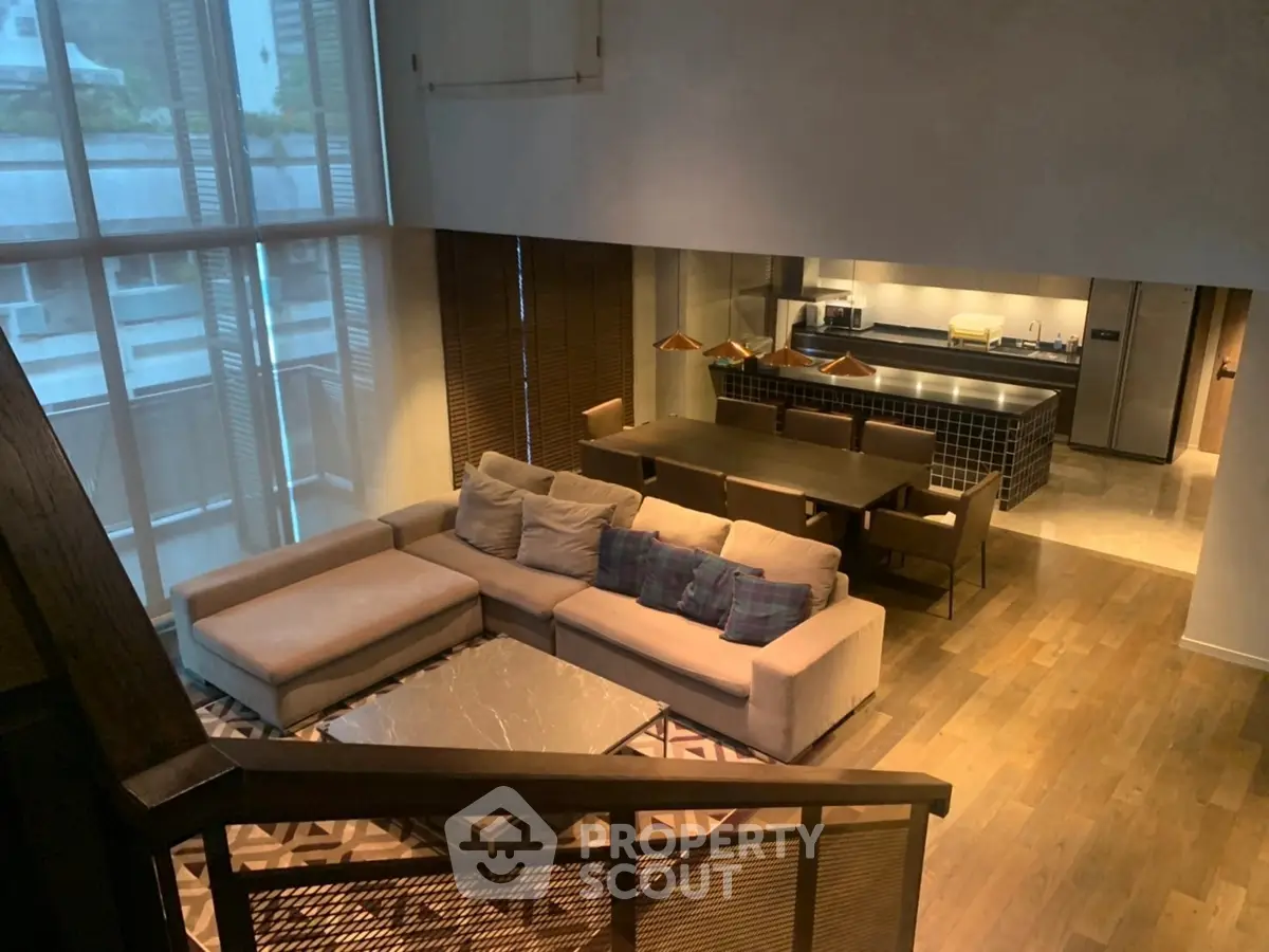 Luxurious open-plan living room with modern kitchen and elegant dining area, featuring floor-to-ceiling windows.