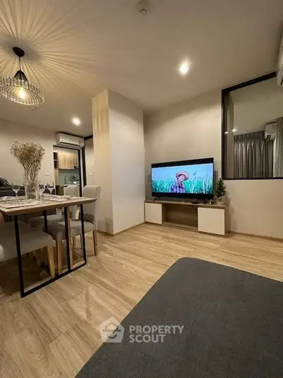 Modern living room with stylish decor and open dining area, featuring wooden flooring and ambient lighting.