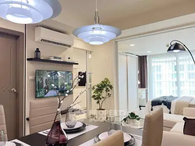 Modern open-plan living and dining area with stylish decor and view into a cozy bedroom.