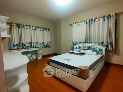 Spacious bedroom with floral curtains and modern furnishings, perfect for a cozy retreat.