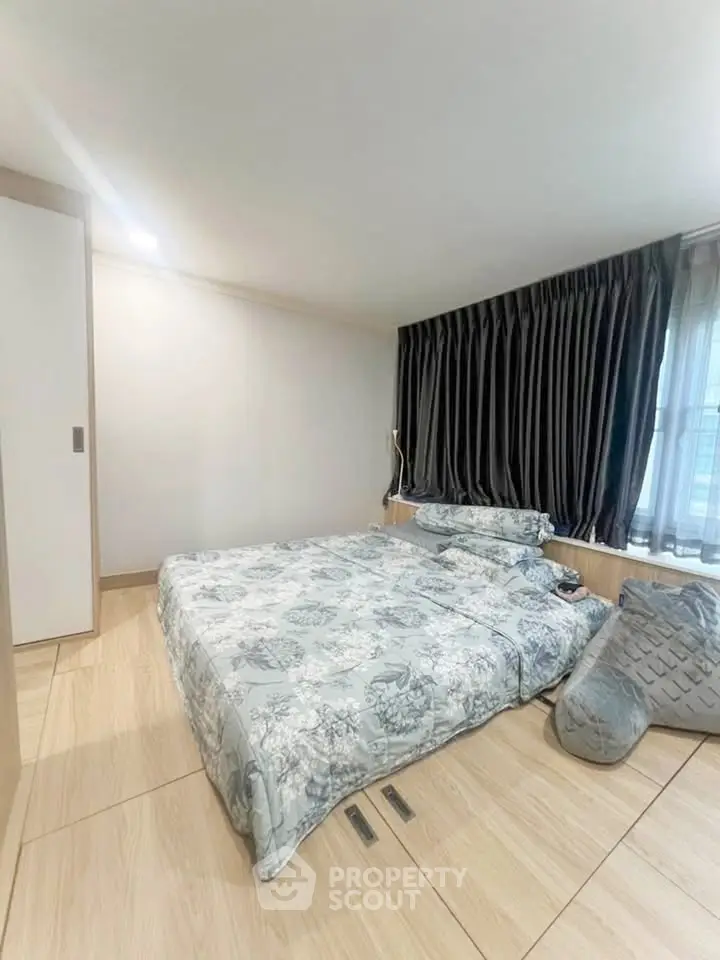 Cozy bedroom with modern decor and large window, featuring elegant curtains and stylish bedding.