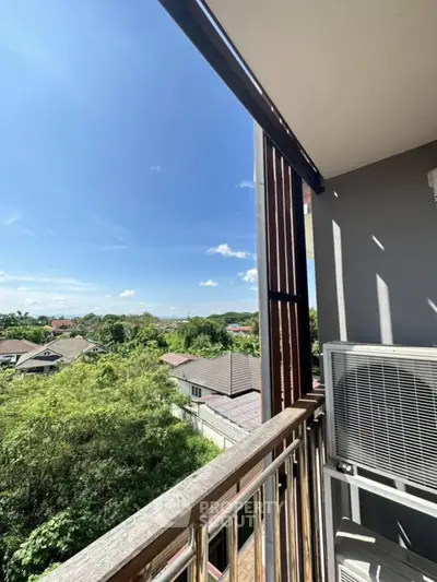 Charming balcony view with lush greenery and clear blue sky, perfect for relaxation and enjoying nature.
