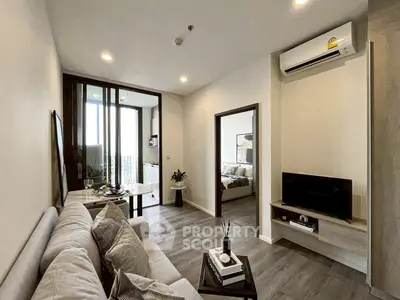 Modern living room with cozy sofa, stylish decor, and open view to bedroom and balcony.