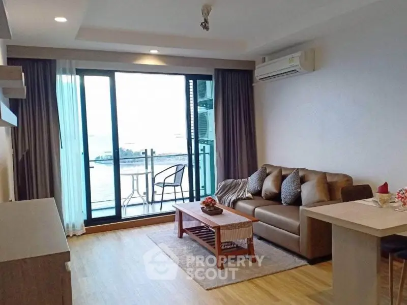 Modern living room with balcony and sea view, featuring stylish furniture and air conditioning.
