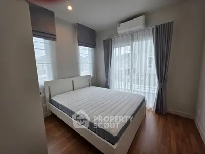Modern bedroom with large windows and natural light, featuring a comfortable bed and stylish curtains.