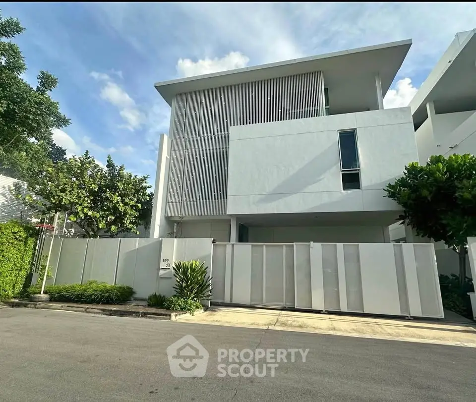 Modern white building exterior with sleek design and lush greenery