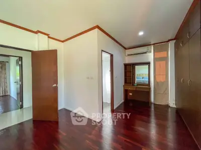 Spacious bedroom with wooden flooring and built-in wardrobe in modern apartment.