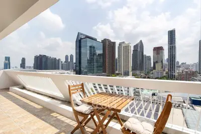 Stunning city view from a spacious balcony with modern outdoor seating, perfect for relaxation.