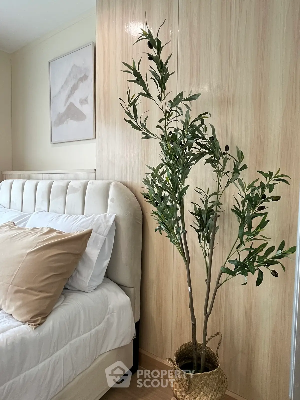 Elegant bedroom with plush bed and stylish decor featuring a potted plant for a serene ambiance.