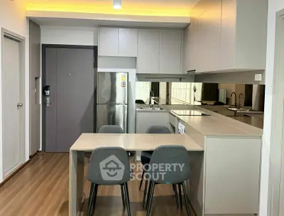 Modern kitchen with sleek design, featuring a dining area and stainless steel appliances.