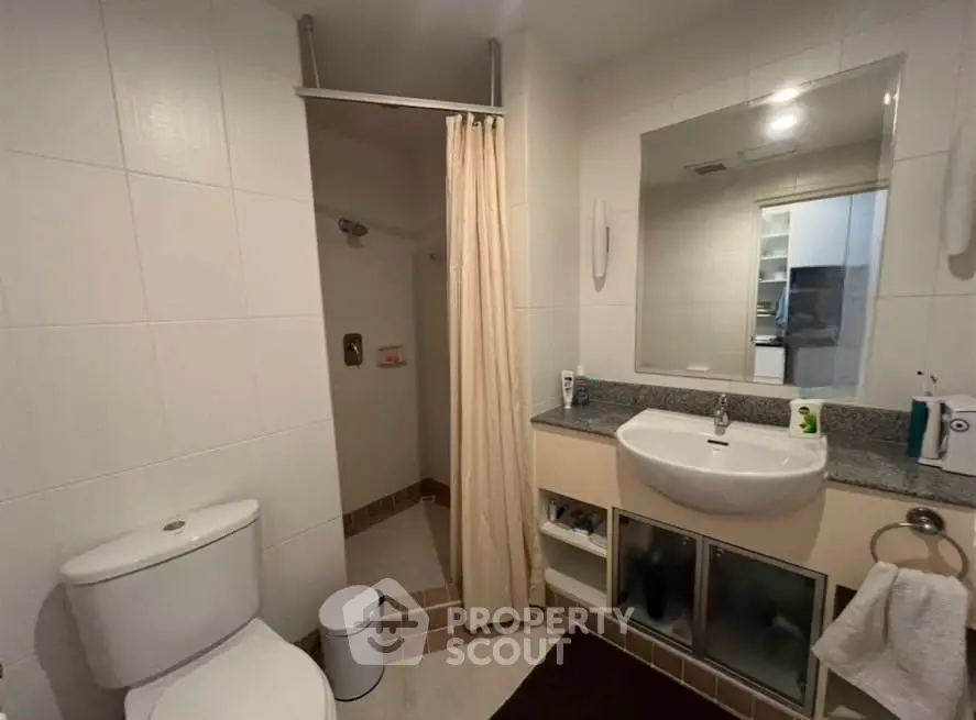 Modern bathroom with shower, sink, and toilet in a sleek real estate property.