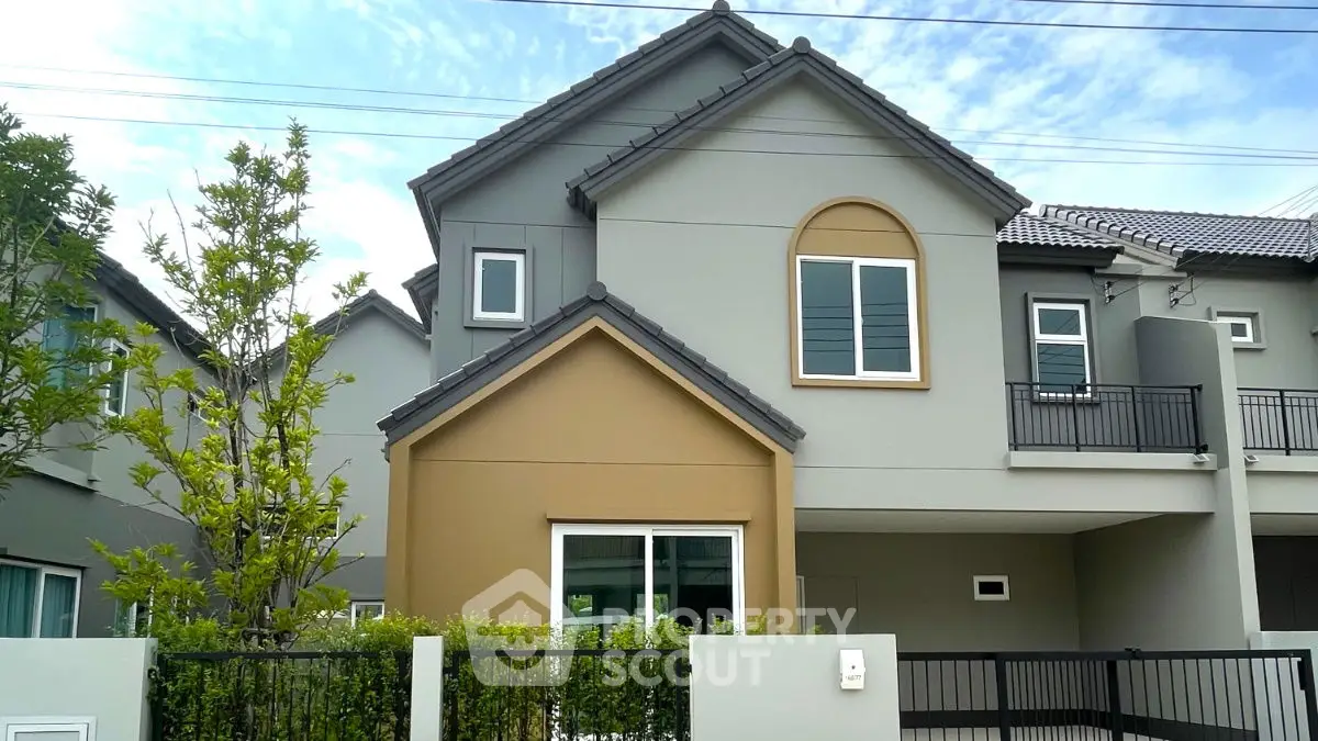 Modern two-story house with stylish facade and lush greenery in a serene neighborhood.