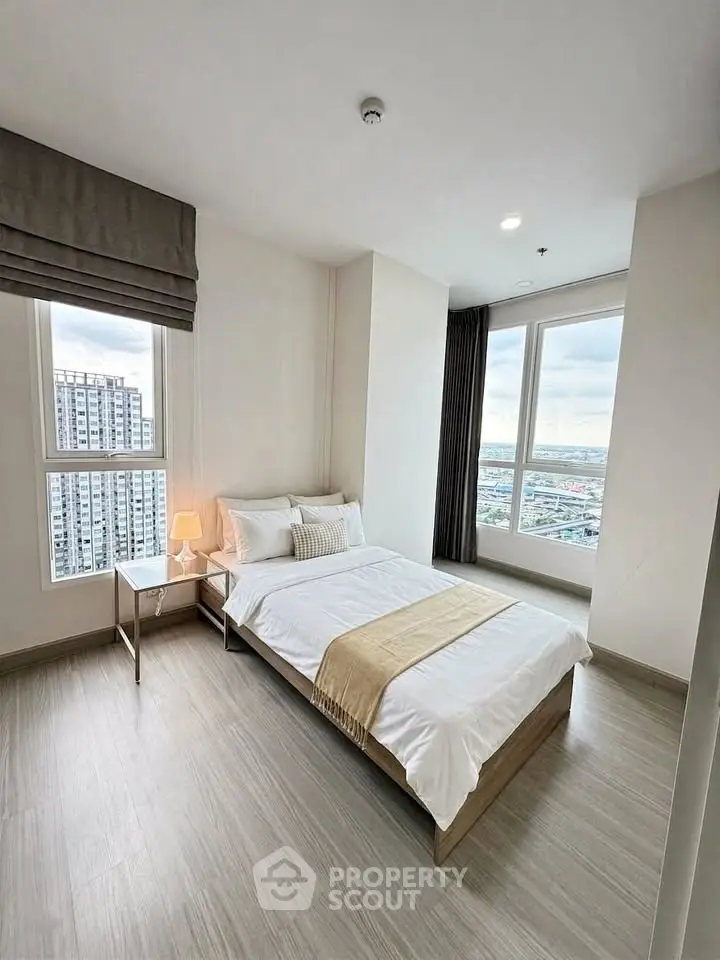 Modern bedroom with city view in high-rise apartment, featuring stylish decor and natural light.