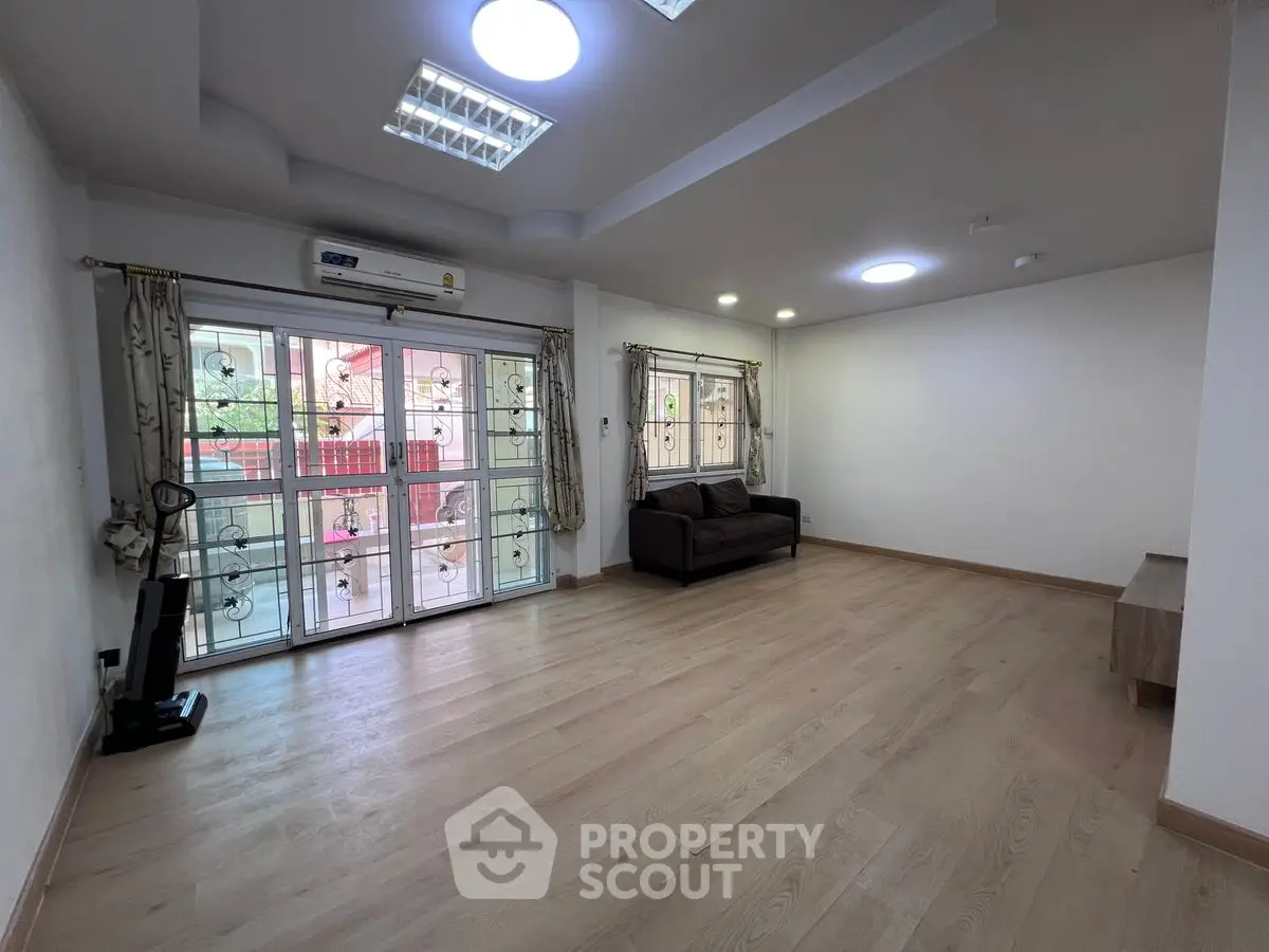 Spacious living room with large windows and wooden flooring in modern apartment
