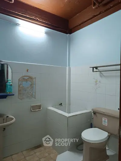Cozy bathroom with tiled walls and compact layout, featuring a bathtub and essential fixtures.