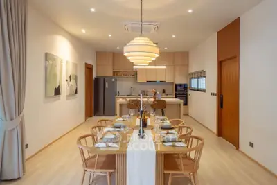 Modern dining area with elegant lighting and open kitchen layout in a stylish apartment.
