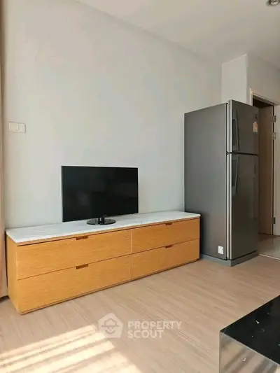 Modern living room with sleek TV stand and stainless steel fridge, perfect for urban living.