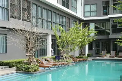 Modern apartment complex with inviting pool and sun loungers, perfect for relaxation and leisure.