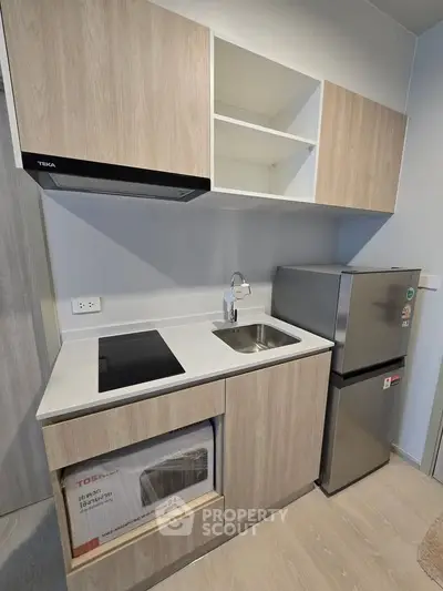 Modern compact kitchen with sleek cabinetry and stainless steel appliances in a stylish apartment.