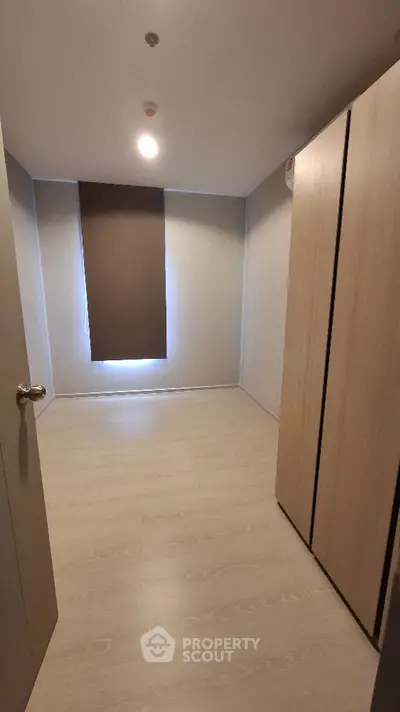 Minimalist bedroom with wooden flooring and large wardrobe, perfect for modern living.