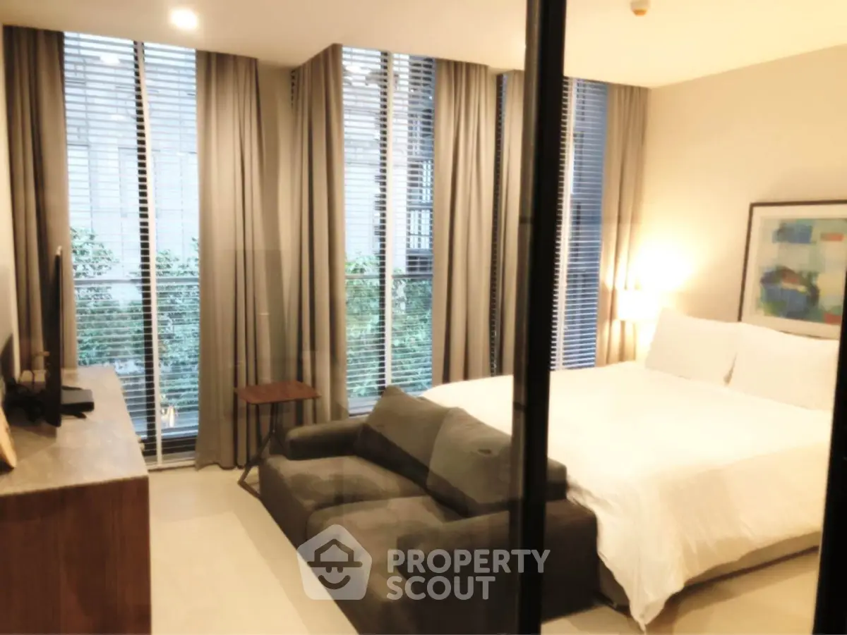 Modern bedroom with large windows and stylish decor in a luxury apartment.
