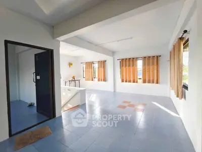 Spacious sunlit room with large windows and tiled flooring, perfect for versatile living space.